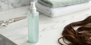 Moisture leave-in conditioner spray for dry hair on sale, next to brown hair on a marble counter.