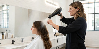 Stylist applies a smoothing blow dry mist to hair for a faster, frizz-free salon blowout.