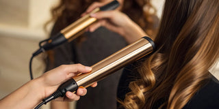 A woman using styling & finishing techniques to create perfect waves with a curling iron.